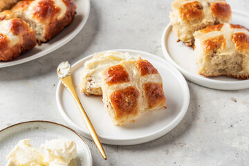 Traditional Easter hot cross buns on white plate with butter on light gray background. Delicious Easter breakfast