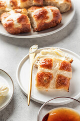 Traditional Easter hot cross buns on white plate with butter on light gray background. Delicious Easter breakfast