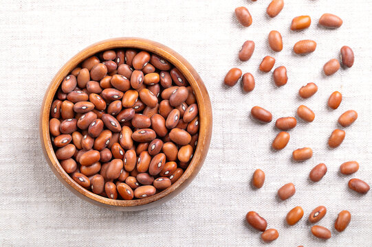 Dutch brown beans in a wooden bowl on linen. Bruine bonen in Dutch, dried variety of bean, Phaseolus vulgaris. Oval shaped and caramel brown in color. Used for baking, boiling, or in soups and stews.