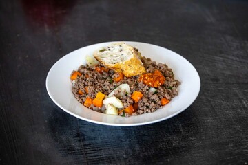 Traditional dish with ground beef and vegetables on an old plate and rustic surface, real food. Brazilian food