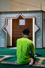 Man Praying Inside Mosque on Carpet with Islamic Art Decoration