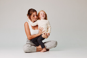 Mother and daughter bonding time sitting on floor against gray background in relaxing atmosphere