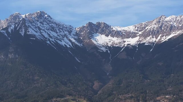 Aerial view of the Bergisel Ski Jump in Innsbruck, Austria, with gradual motion showcasing its modern design and the surrounding snow capped Alps.