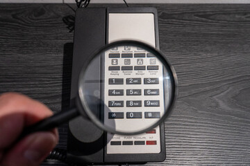 Examining Hotel Phone Keypad with Magnifying Glass for Detail Focus