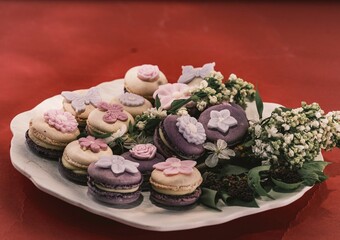 A beautifully arranged platter features an assortment of macarons, each topped with floral decorations, perfect for a charming gathering
