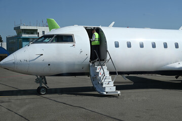 Aircraft parked on the runway with crew members preparing for departure at a regional airport...
