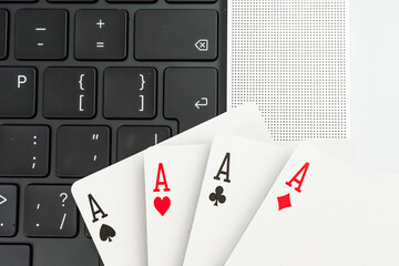 A split image featuring a laptop showing code and playing cards in a fan shape on the right side The context suggests themes of technology, gambling, chance, gaming, business, decisions, uncertainty