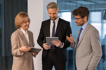 Three business people discussing work together using a tablet in a modern office