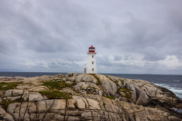 Photo of red and white lighthouse on the rolling granite rocks on the shore if Peggy's Cove in Nova...