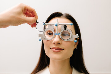Trial frame glasses to determine the correct prescription lenses. Girl is wearing trial frame glasses for eye exam vision test by ophthalmologist. © Rabizo Anatolii