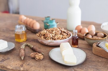 Freshly made butter is showcased on a rustic wooden table surrounded by a variety of ingredients like eggs, nuts, and honey, all ready for delicious baking endeavors