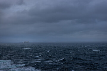 Fototapeta premium Stormy overcast cloudy ocean cruise ship on the horizon 