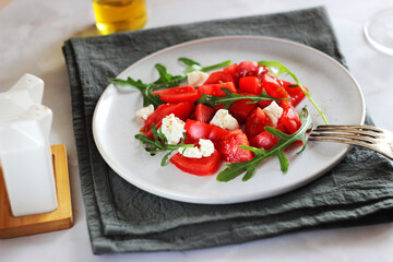 Tomato salad with arugula and cheese in a plate on the table