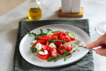 Tomato salad with arugula and cheese in a plate on the table