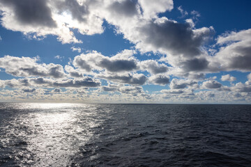 Obraz premium Beautiful clouds sunlit over an alluring calm ocean horizon.