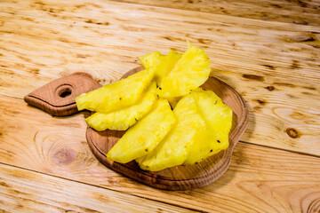 Cutting board with sliced pineapple on wooden table