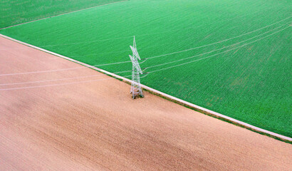 Obraz premium Aerial view with electricity pylon in the middle of agricultural fields