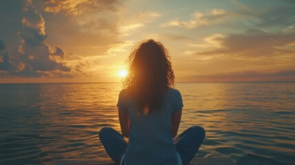Fototapeta premium Young curly Caucasian woman enjoying the sea sunset during vacation, meditation relaxation concept