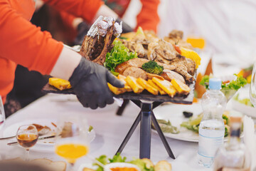 Delightful gathering with beautifully served grilled meat dishes during a festive celebration at a banquet hall. Waiter serving table in the restaurant preparing to receive guests. 