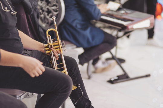 Musicians preparing for a lively performance with brass instruments and keyboards in a vibrant setting filled with anticipation.