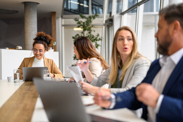Group of professional entrepreneurs discussing strategies with each other while sitting together in board room