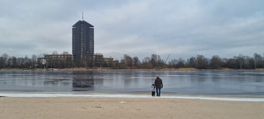 Father and son are checking ice on the river coast. Family walk along the river. Winter in Europe. Panorama of a river.