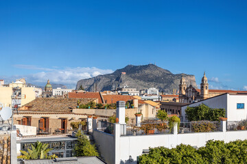 Naklejka premium Vibrant cityscape with a mix of historical and modern architecture, set against a mountainous backdrop