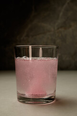 Refreshing pink beverage sparkling in a clear glass on a marble surface
