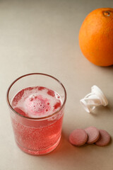 Refreshing fizzy drink beside a vibrant orange in a cozy setting