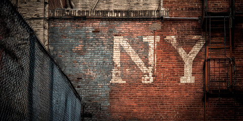 Brick wall texture with faded "NY" lettering, showcasing urban decay and history, representing city life, nostalgia, and aged aesthetics