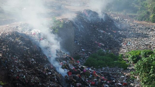 Illegal dump burning with smoke. Pollution by rubbish in landfill
