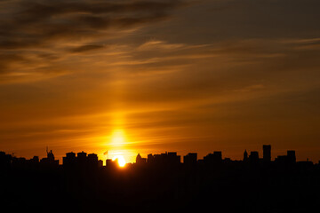The Kyiv skyline is silhouetted against the colors of dusk, with the Motherland Monument visible on the left and city lights beginning to illuminate the darkness below.