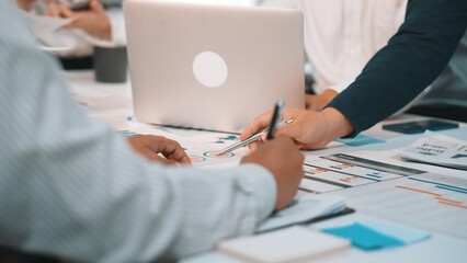 A dynamic business meeting showcasing collaboration among professionals. Focus on data analysis with charts spread on the table and a laptop present, capturing teamwork and strategy development. SACTR
