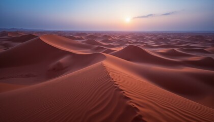Vast sand dunes in warm tones meet a hazy twilight sky, creating a serene and solitary scene.