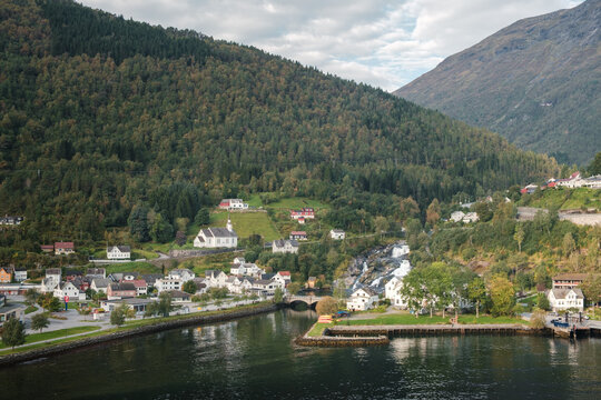 The small Norwegian town Hellesylt in the sunlight with mountains in the background in Norway.