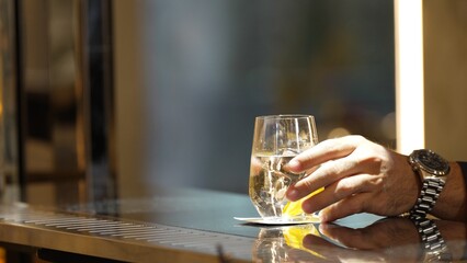 Closeup customer hand placing gin fizz or tonic drink with sliced orange at bar counter club greeting welcome guess waiting friend, refreshing beverage for pub and restaurant advertisement. Vinosity.