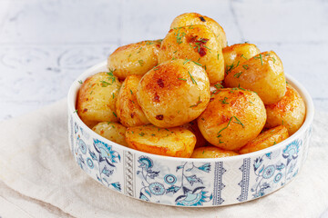 Baked new potatoes, with butter and dill, on a white plate, at home, no people,