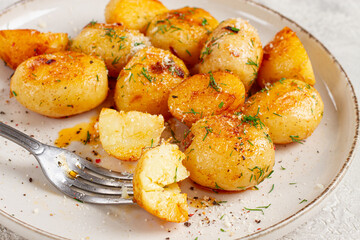 half-eaten fried new potatoes, with butter and dill, on a white plate, with a fork, at home, no people,