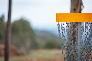 Yellow disc golf basket and blurred backgound.