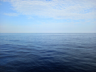 Panoramic view of a calm sea. Background of the horizon with ocean and a blue sky with white clouds. Maritime landscapes. Relaxation and seabeds.
