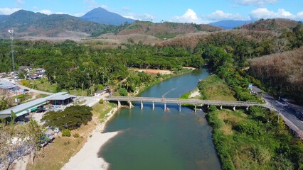 Serene River Bridge: Aerial view of a tranquil river with a bridge. A picturesque scene showcasing the synergy of nature and construction under a clear blue sky.