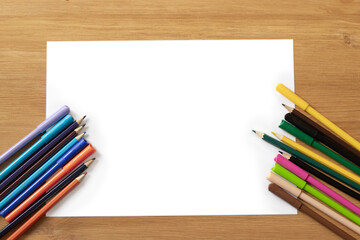 white sheet of paper on a wooden table, colored pencils. Children's creativity