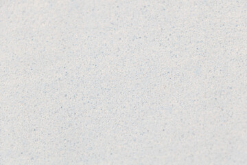 Obraz premium White sand background with small blue specks, light gray and sky-blue tones, close-up, top view,