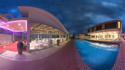 Beautiful beachfront restaurant area featuring a sleek pool, modern architecture, and glowing ambient lights, creating an inviting atmosphere during twilight hours.