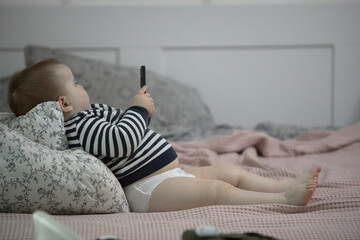 Toddler boy playing with phone on bed