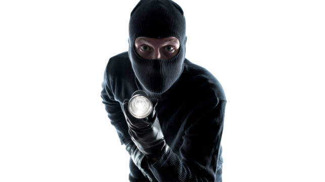 Masked figure with flashlight in dark setting during night hours