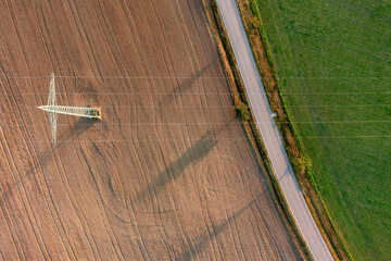 Aerial view with electricity pylon between agricultural fields