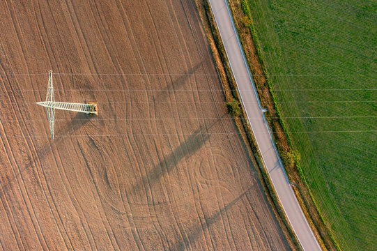 Aerial view with electricity pylon between agricultural fields