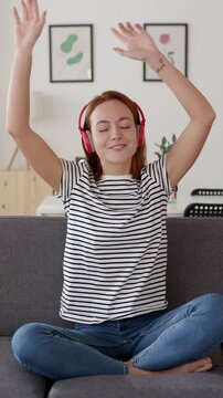 Vertical HD video of happy young woman having fun dancing on sofa at home. Domestic lifestyle and happiness concept
