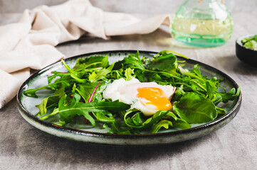 Poached egg in arugula and chard leaves on a plate on a table